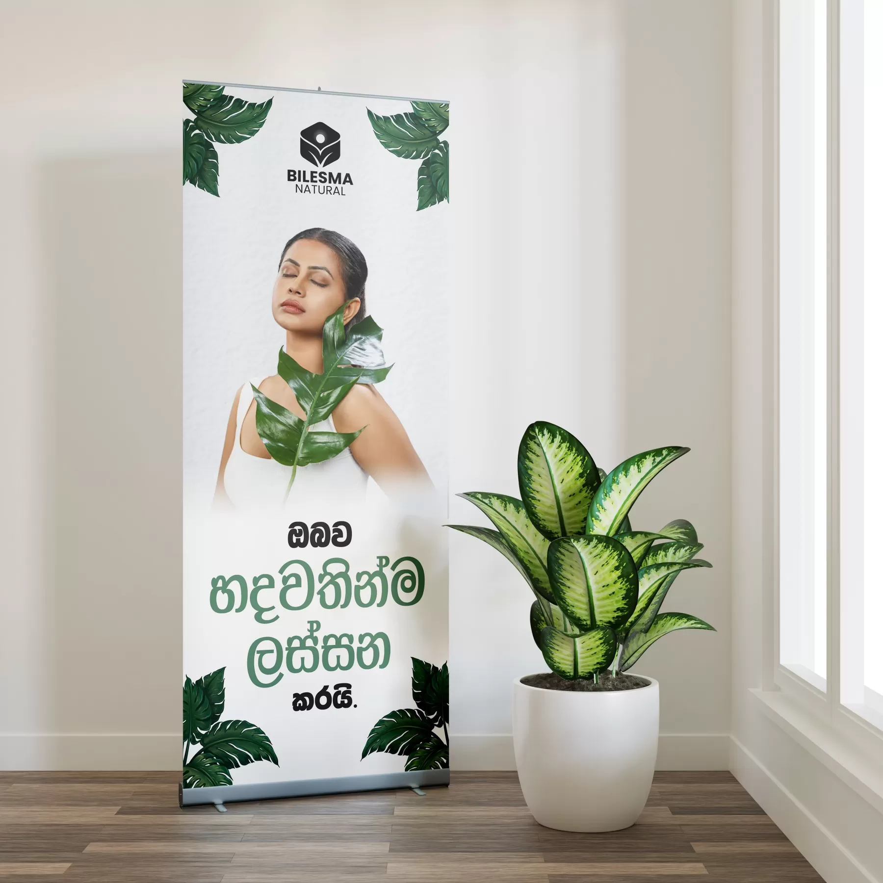 Bilesma Natural X-banner roll-up stand with Sinhala headline, model holding a monstera leaf, designed by Uniix Studio